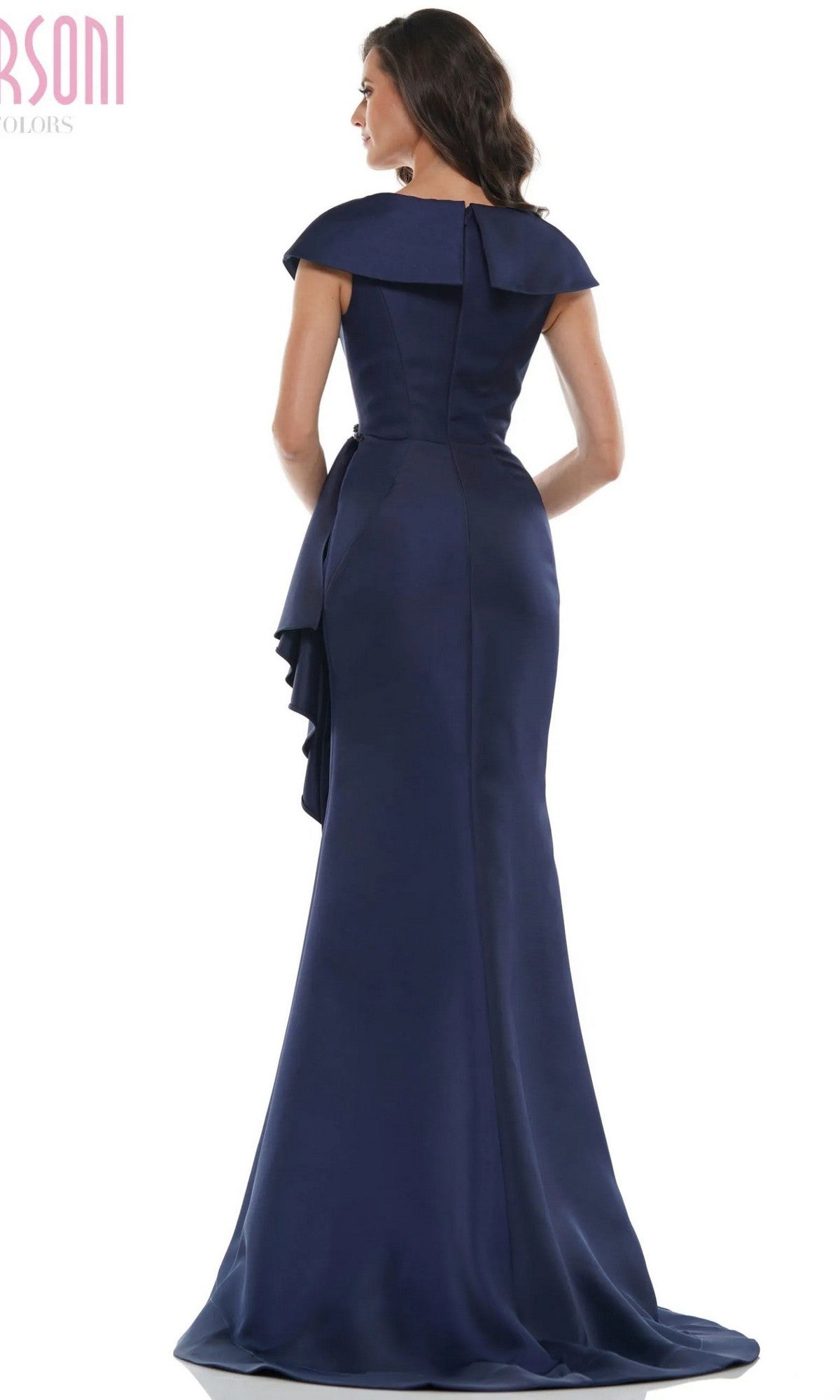 A woman stands facing away, wearing the Marsoni MV1086—a navy blue, floor-length, off-shoulder formal dress with a fitted bodice, beaded embellishments, and a draped back detail.